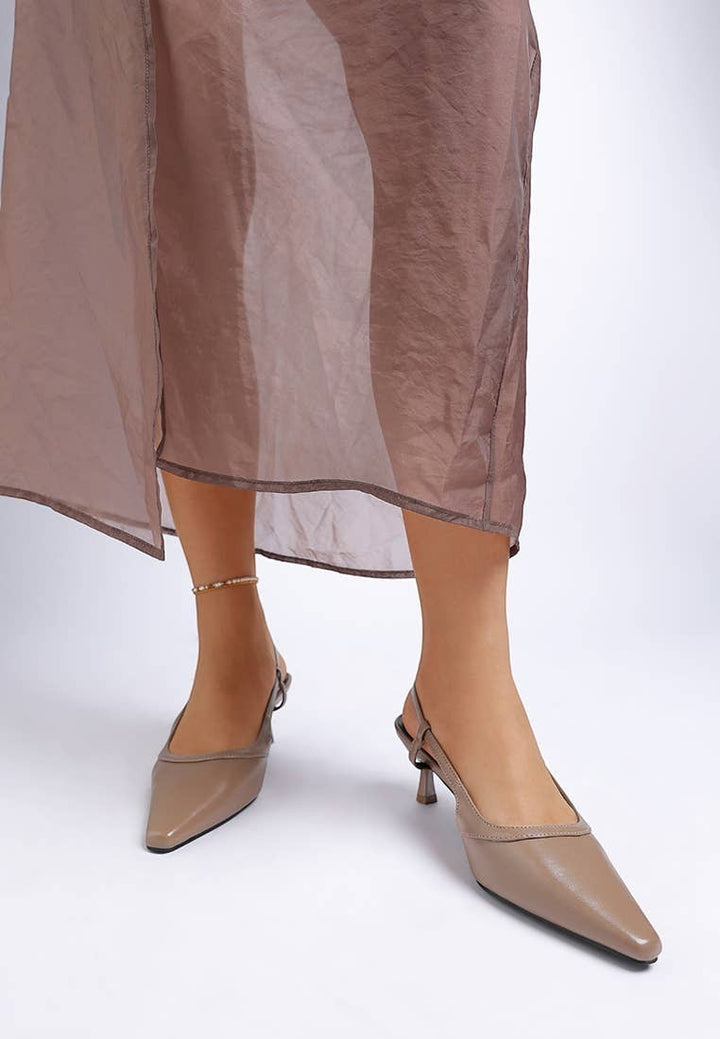 A Styled Collective beige faux leather slingback kitten heels with a snip toe and buckle strap worn by a model.