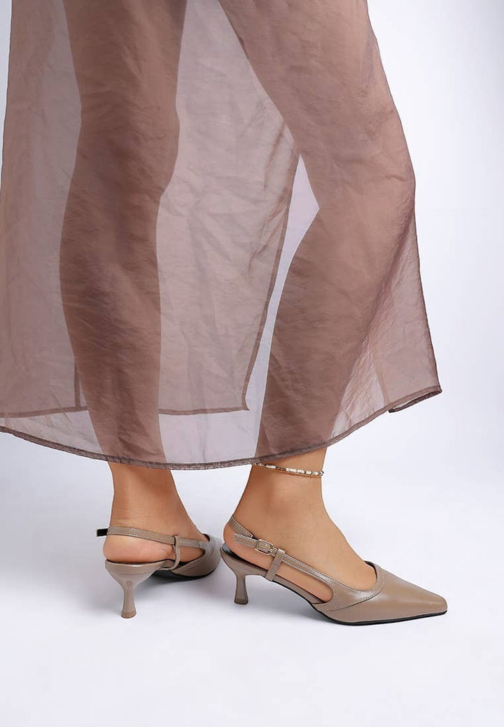 A Styled Collective beige faux leather kitten heel slingbacks with a snip toe and adjustable buckle strap on a model.