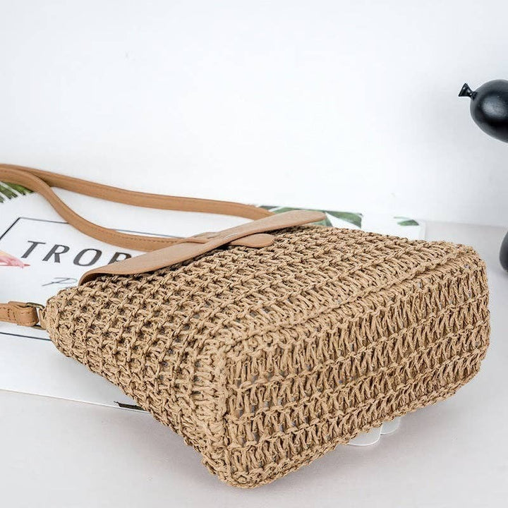 A Styled Collective beige woven straw crossbody bag with a tan leather-look strap and flap closure for summer style.